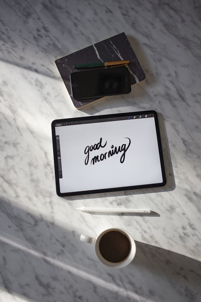 Flat lay of a stylish workspace with a tablet, coffee, and stationery on a marble table.